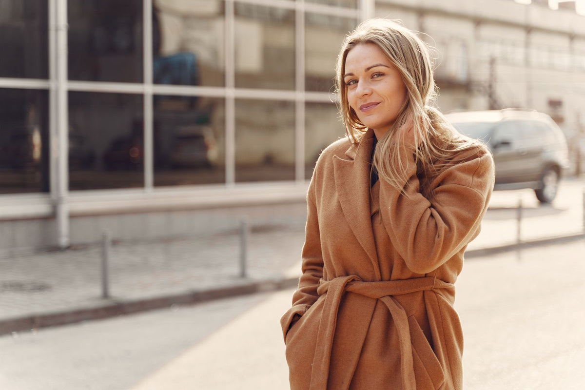 Woman wearing a camel wrap coat on a city street